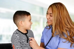 Female Hispanic nurse listening to a child's heartbeat